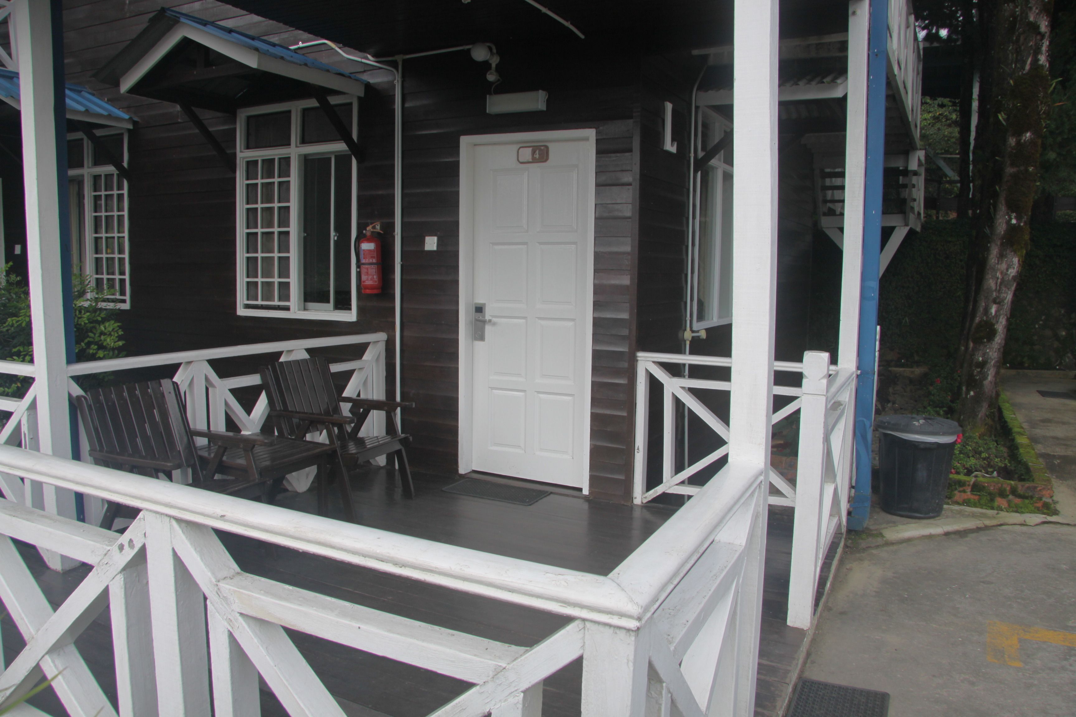 A wooden cabin with a porch, a white door, and a fire extinguisher.