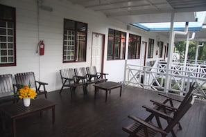 A covered porch with wooden furniture, including chairs and a table, and a fire extinguisher mounted on the wall. - Kinabalu Pine Resorts (Ranau)