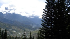 A wooden deck with benches and flower planters, overlooking a mountainous landscape with a clear sky. - Kinabalu Pine Resorts (Ranau)