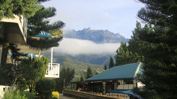 A traditional Japanese building with a covered walkway, surrounded by lush greenery and mountains in the background. - Kinabalu Pine Resorts (Ranau)