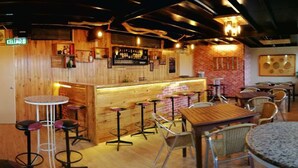 A restaurant with a bar area, wooden walls, and multiple seating options including bar stools and tables. - Kinabalu Pine Resorts (Ranau)