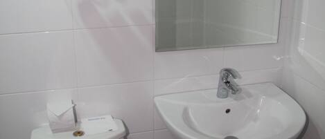 A bathroom with a toilet, sink, and mirror.