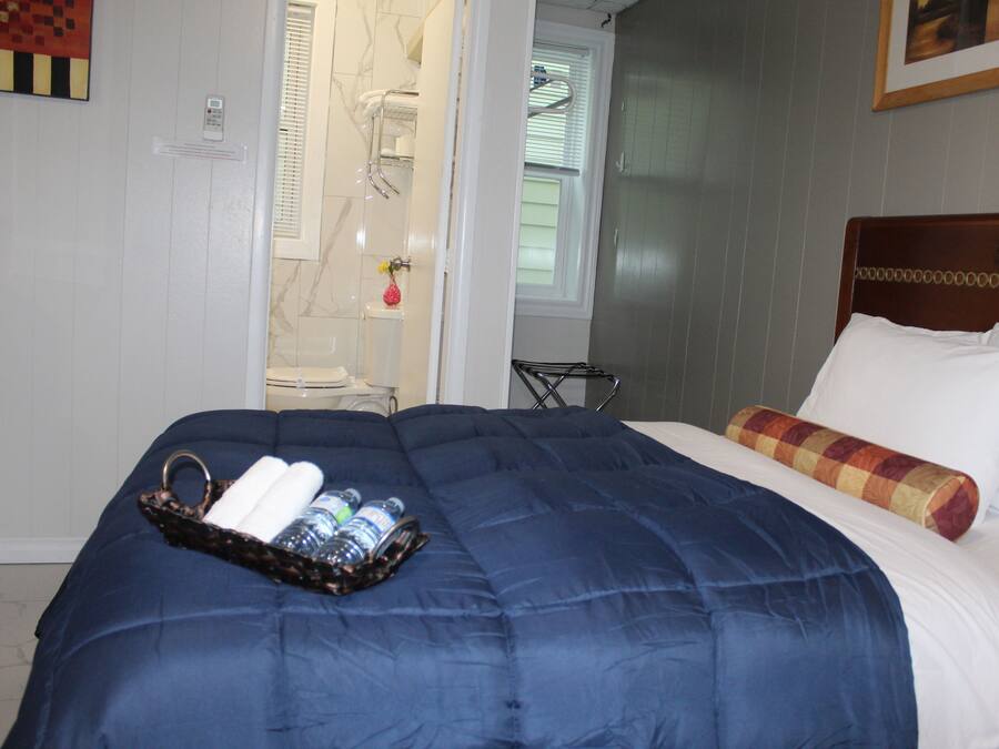 Ett hotellrum med en säng, ett nattduksbord, en dusch och ett fönster.