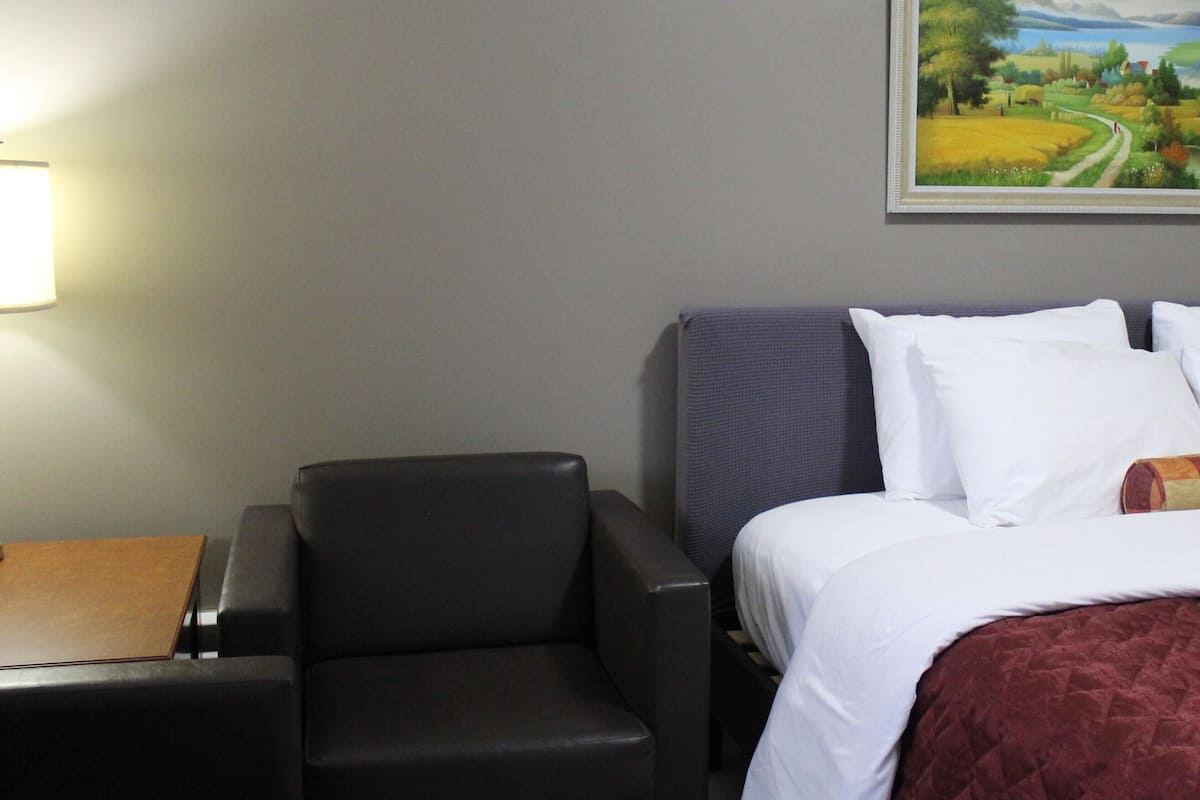 Una habitación de hotel con cama, escritorio, silla y un cuadro en la pared.