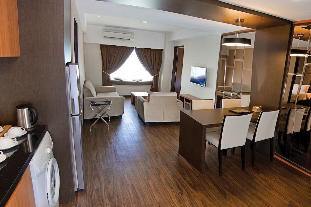 A modern hotel room with a kitchen area, a dining space, and a bedroom.