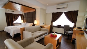 A hotel room with two beds, a sofa, a small table with a flower arrangement, a chair, and a desk with a telephone. - C'haya Hotel (Kota Kinabalu)