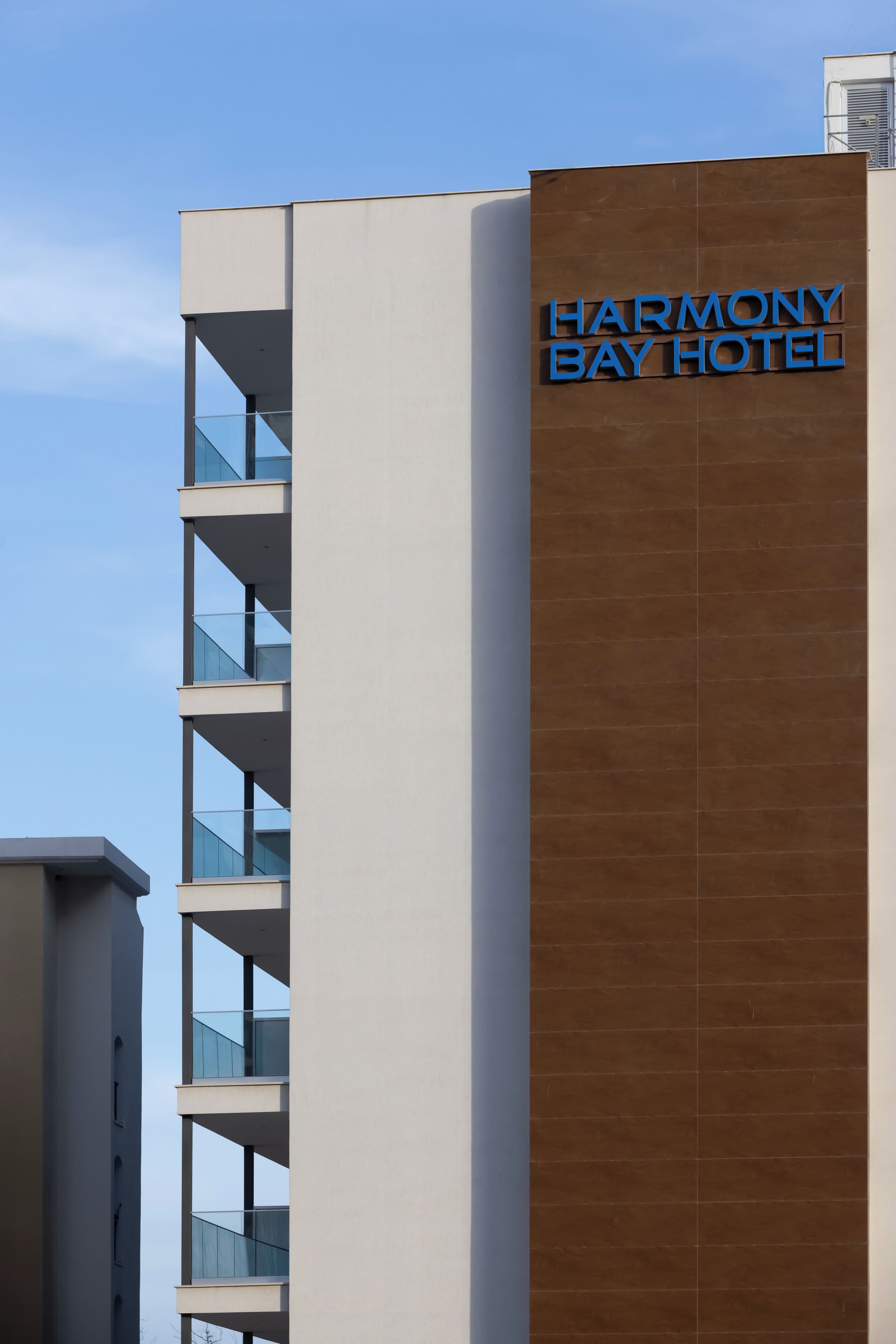 A modern building with a sign reading 'HARMONY BAY HOTEL.'