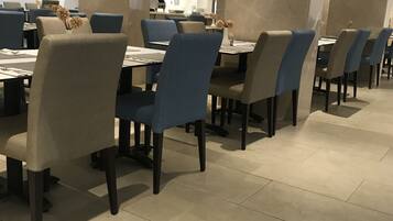 Un espace de restauration moderne avec des chaises bleues et beiges, des piliers en marbre et un sol carrelé.