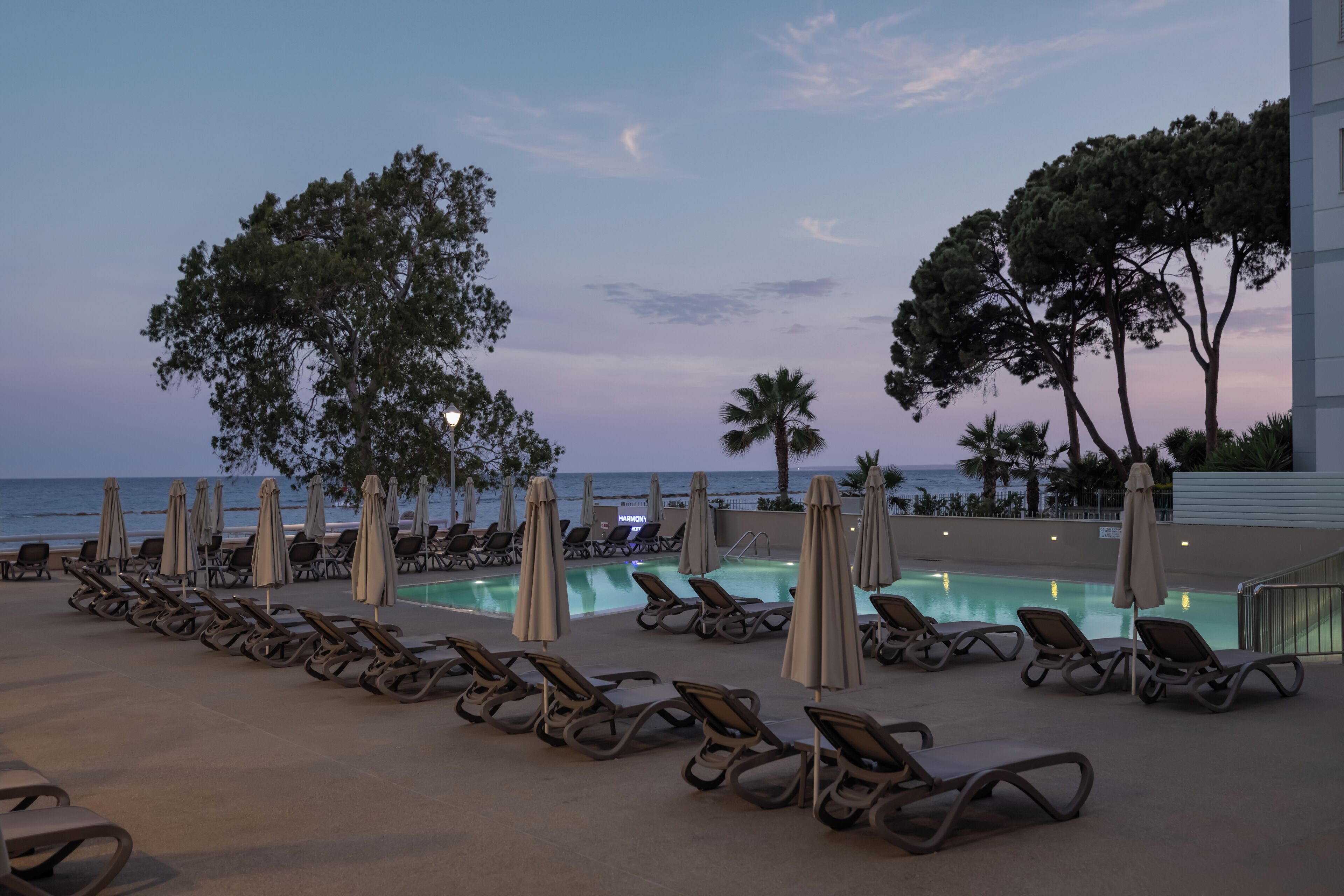 A poolside area with lounge chairs and umbrellas, overlooking the ocean.