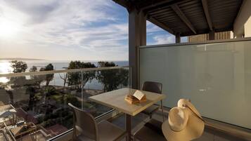 A balcony with a table, chairs, and a hat.