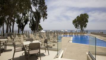 A poolside area with lounge chairs and umbrellas, overlooking a body of water.