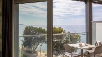 A modern living room with a large sliding glass door leading to a balcony with a view of the sea.