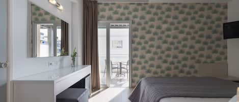 A hotel room with a bed, a desk, a mirror, a TV, and a balcony with a view.