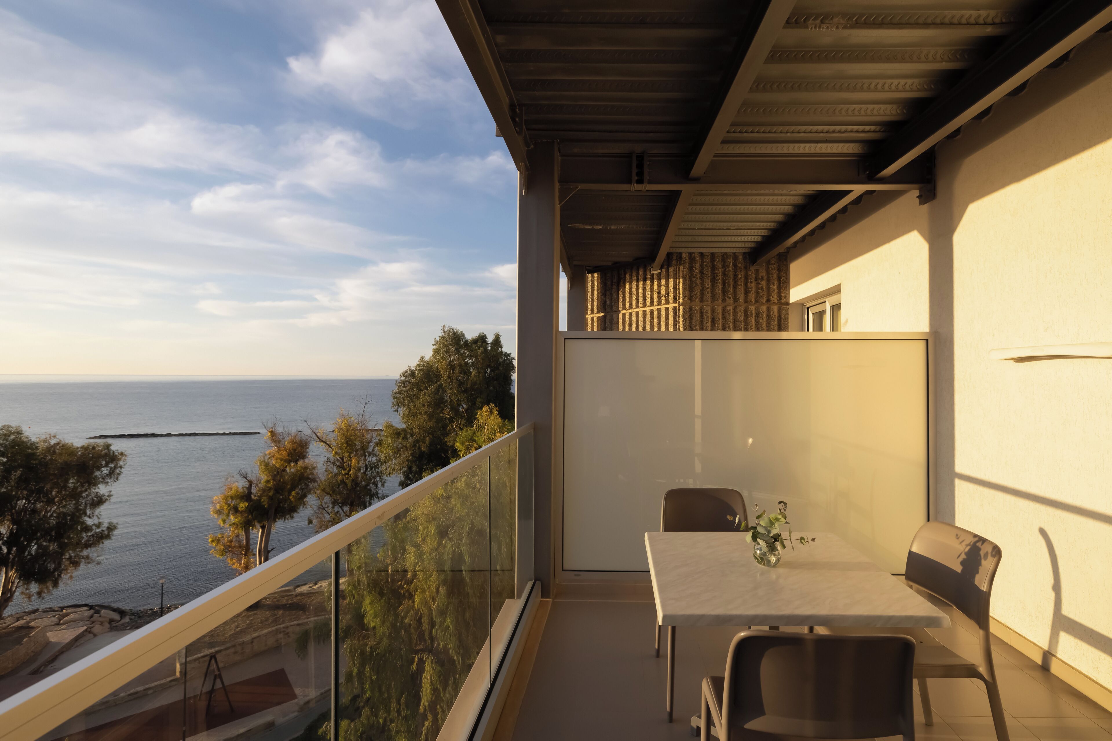A balcony with a table and chairs, overlooking a body of water and trees.