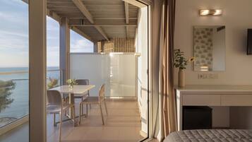 Ein modernes Zimmer mit Balkon, einem Essbereich, einem Bett, einem Schreibtisch und einem Spiegel.