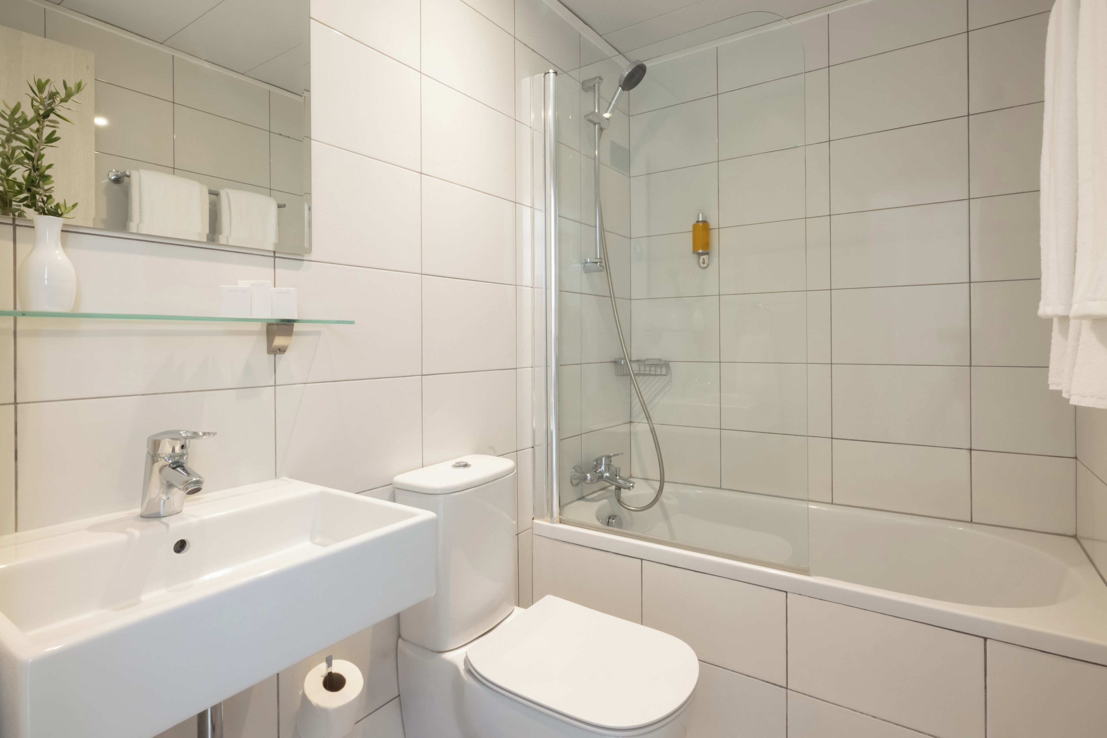 A modern bathroom with a glass-enclosed shower, a white sink, and a toilet.