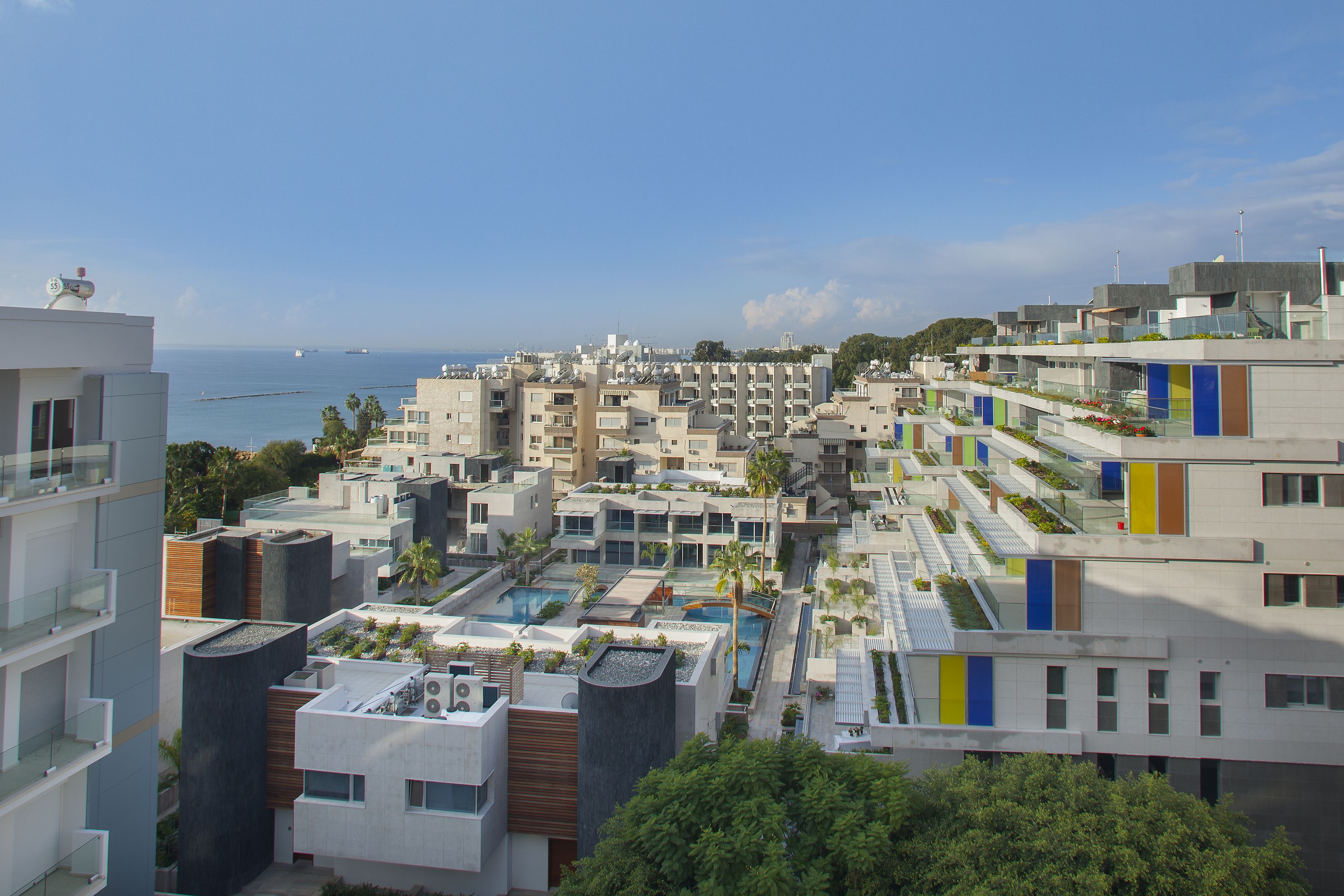 Un moderno complejo hotelero con varias construcciones, piscinas en la azotea y vista al mar.