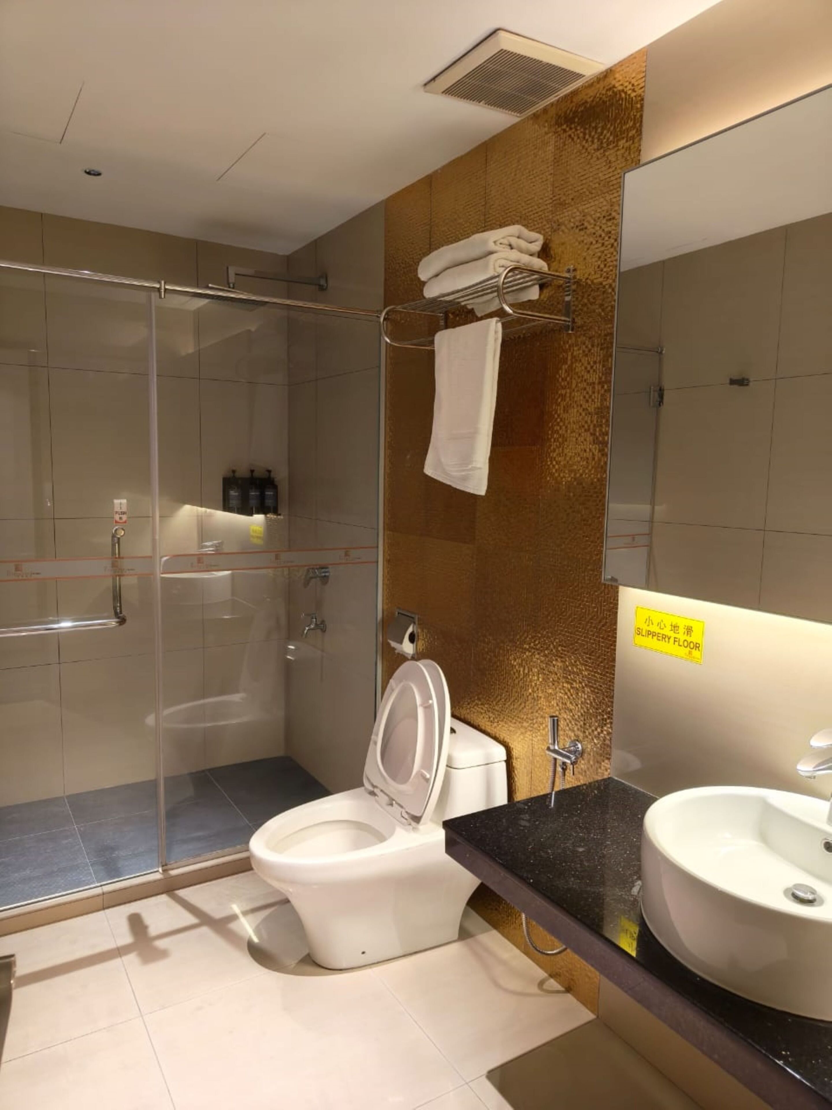 Un bagno moderno con cabina doccia in vetro, un water e un lavandino.