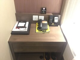 A wooden desk with a black telephone, a yellow box, and a remote control.