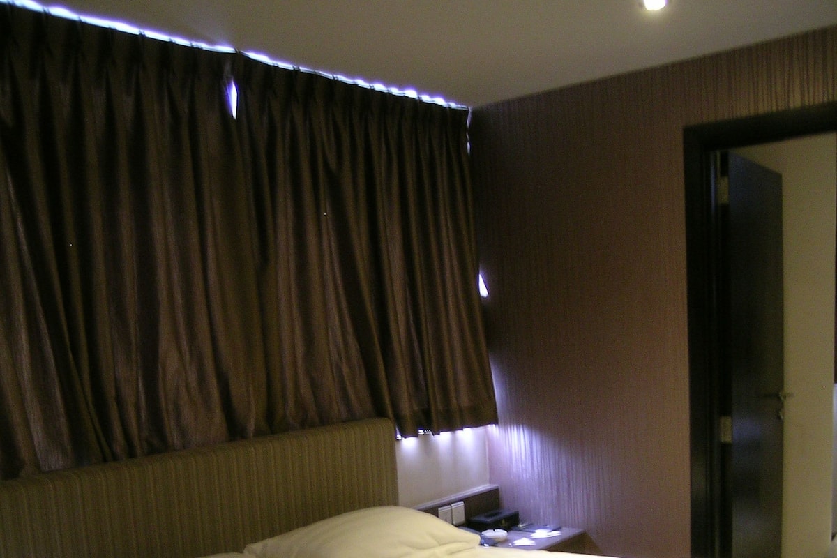 A hotel room with a large bed, a nightstand, and a door.