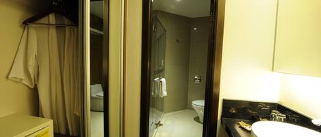 A hotel bathroom with a glass-enclosed shower, a white sink, and a mirror.