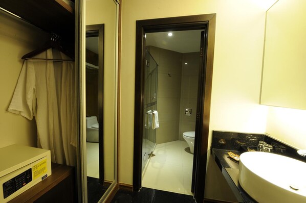 A hotel bathroom with a glass-enclosed shower, a white sink, and a mirror. - The Imperial Hotel (Kluang)