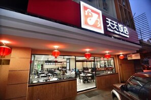 Un restaurant avec une enseigne rouge et blanche, des tables en terrasse et des lanternes rouges.