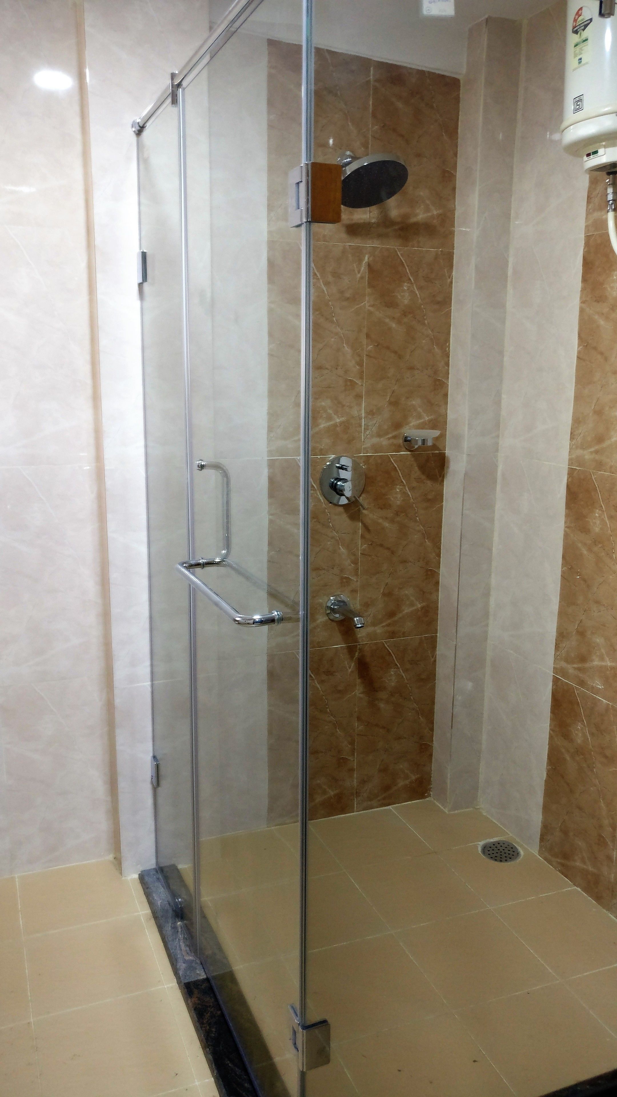 A glass-enclosed shower stall with a handheld showerhead, a handheld showerhead, and a wall-mounted showerhead.