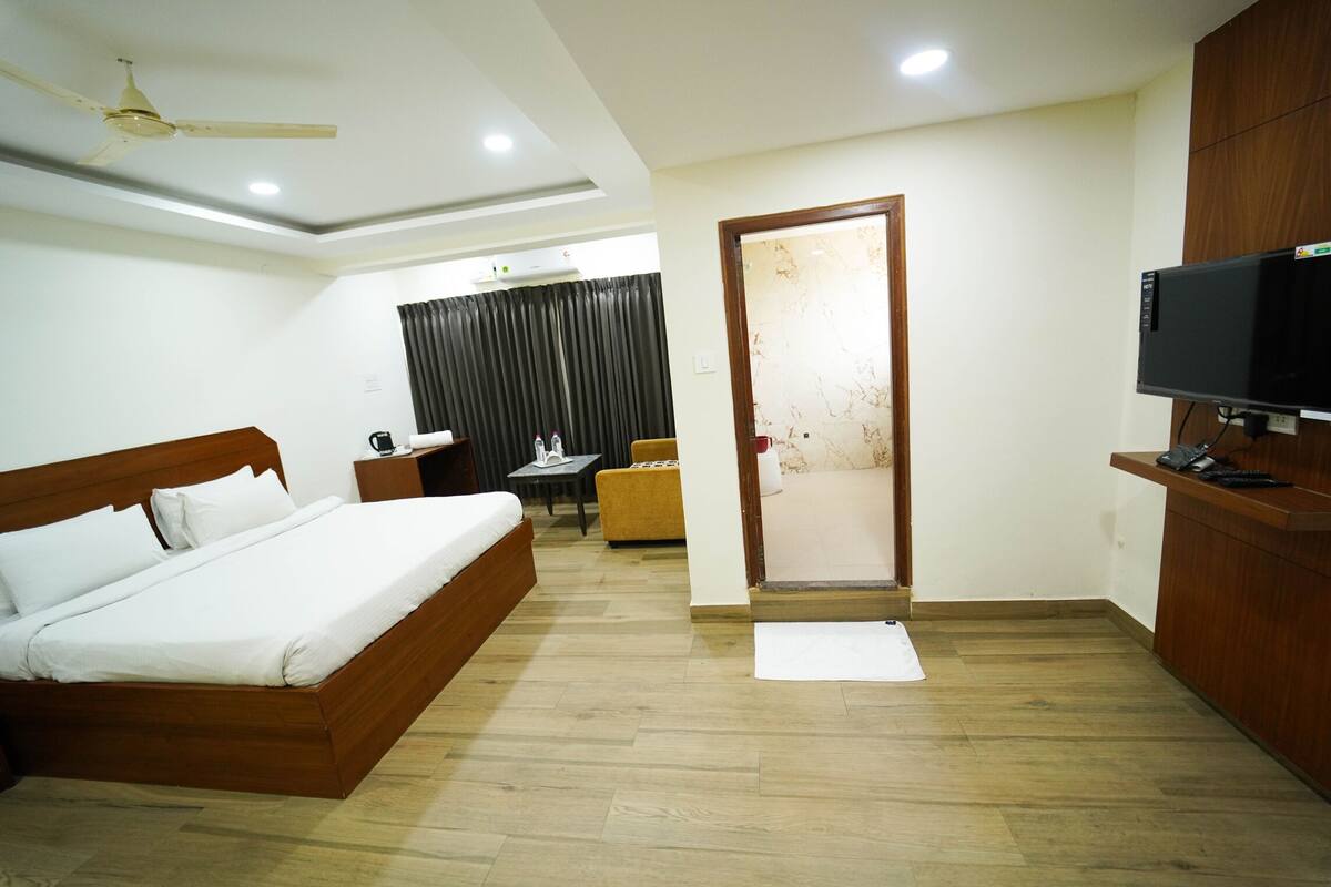 A hotel room with a wooden bed, a TV, a desk, and a chair.