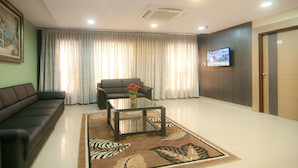 A living room with a sofa, a glass coffee table, a zebra-patterned rug, and a television mounted on the wall. - Shoba Inn (Bengaluru)