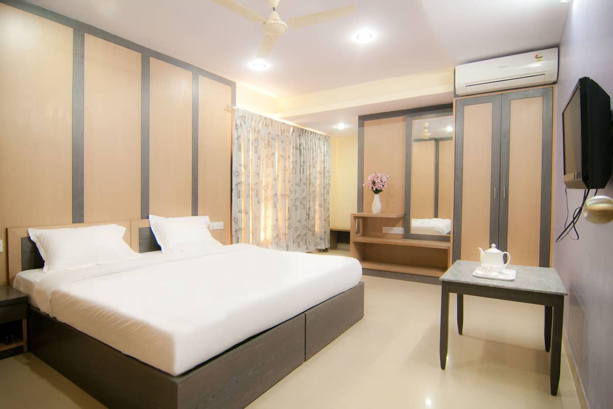 A hotel room with a bed, bedside table, air conditioning unit, and a television.