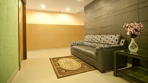 A modern living room with a sofa, a glass coffee table, and a decorative vase. - Shoba Inn (Bengaluru)