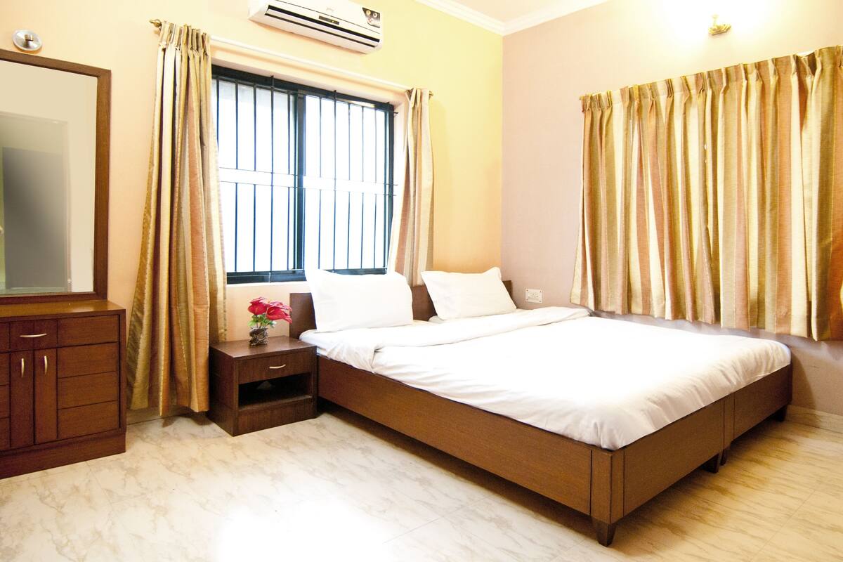 A bedroom with a bed, nightstand, dresser, and window with curtains.