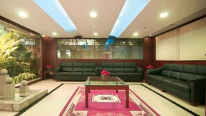 A modern living room with two green sofas, a glass coffee table, and a decorative rug. - Shoba Suites (Bengaluru)