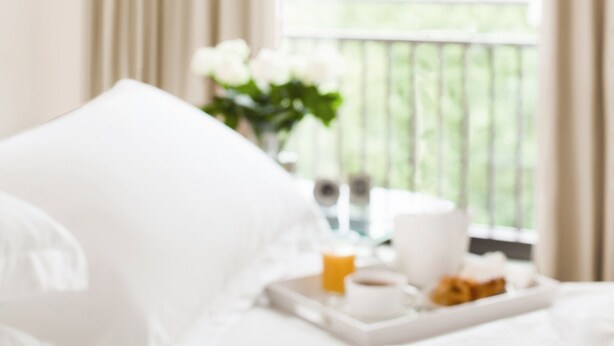 A bed with white bedding and a tray of breakfast items including orange juice, coffee, and pastries. - Shoba Suites (Bengaluru)