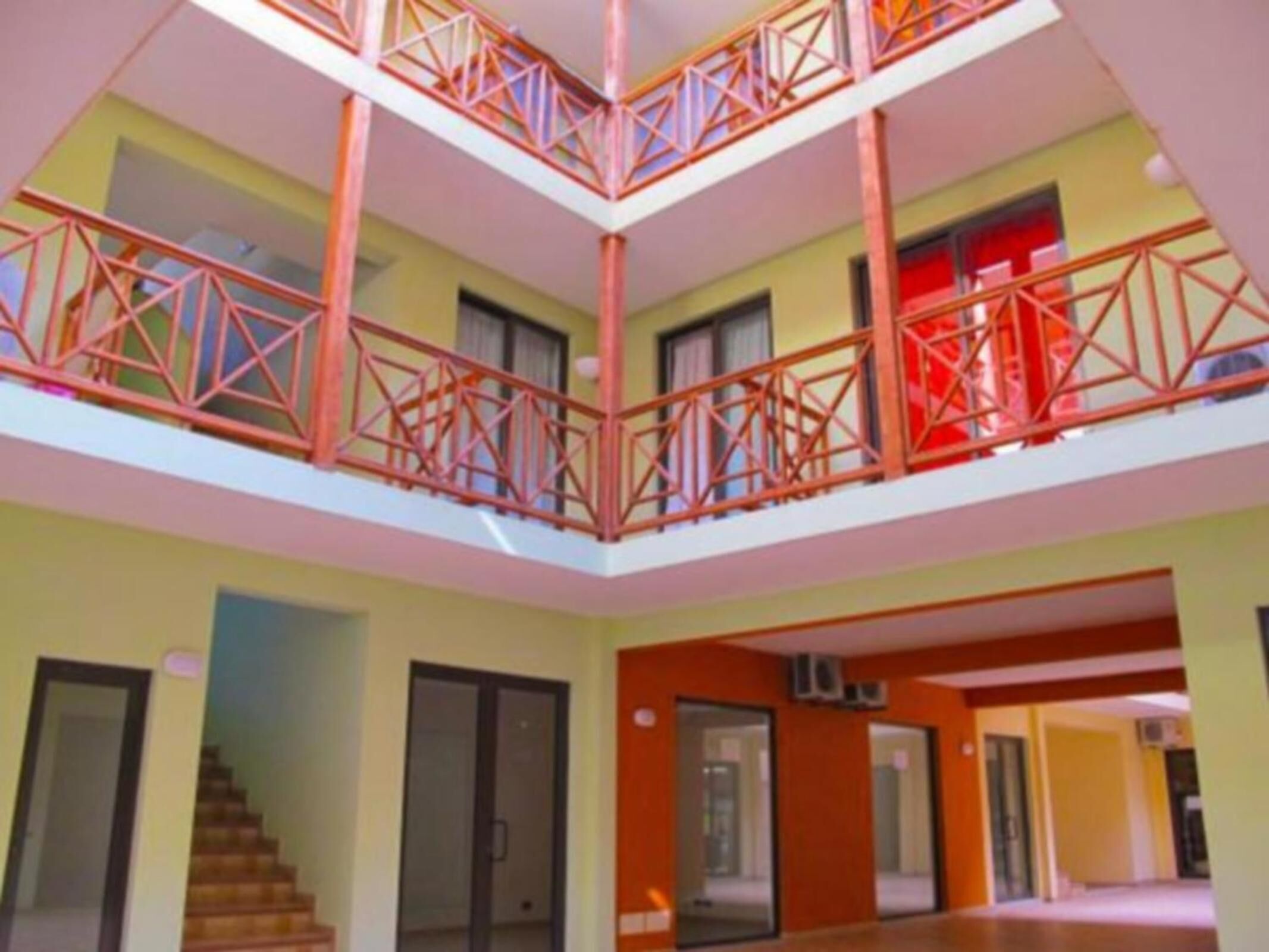 A multi-level interior with a central atrium, balconies with red railings, and a staircase.