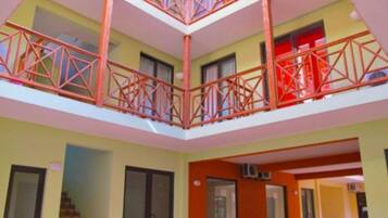A multi-level interior with a central atrium, balconies with red railings, and a staircase.