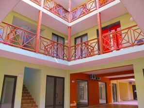 A multi-level interior with a central atrium, balconies with red railings, and a staircase. - Patio Antigo Residence (Sal)