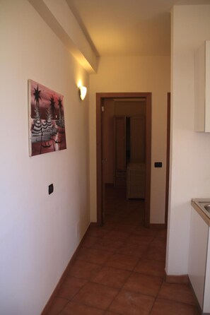 A hallway with a tiled floor, a painting on the wall, and a door leading to another room. - Patio Antigo Residence (Sal)