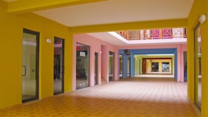 A brightly colored corridor with a tiled floor, glass doors, and a skylight. - Patio Antigo Residence (Sal)