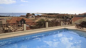 A swimming pool with a tiled deck and a view of the beach and ocean. - Patio Antigo Residence (Sal)