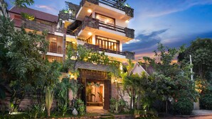A two-story building with a balcony and a garden in front. - Cambana d'Angkor Suites (Siem Reap)