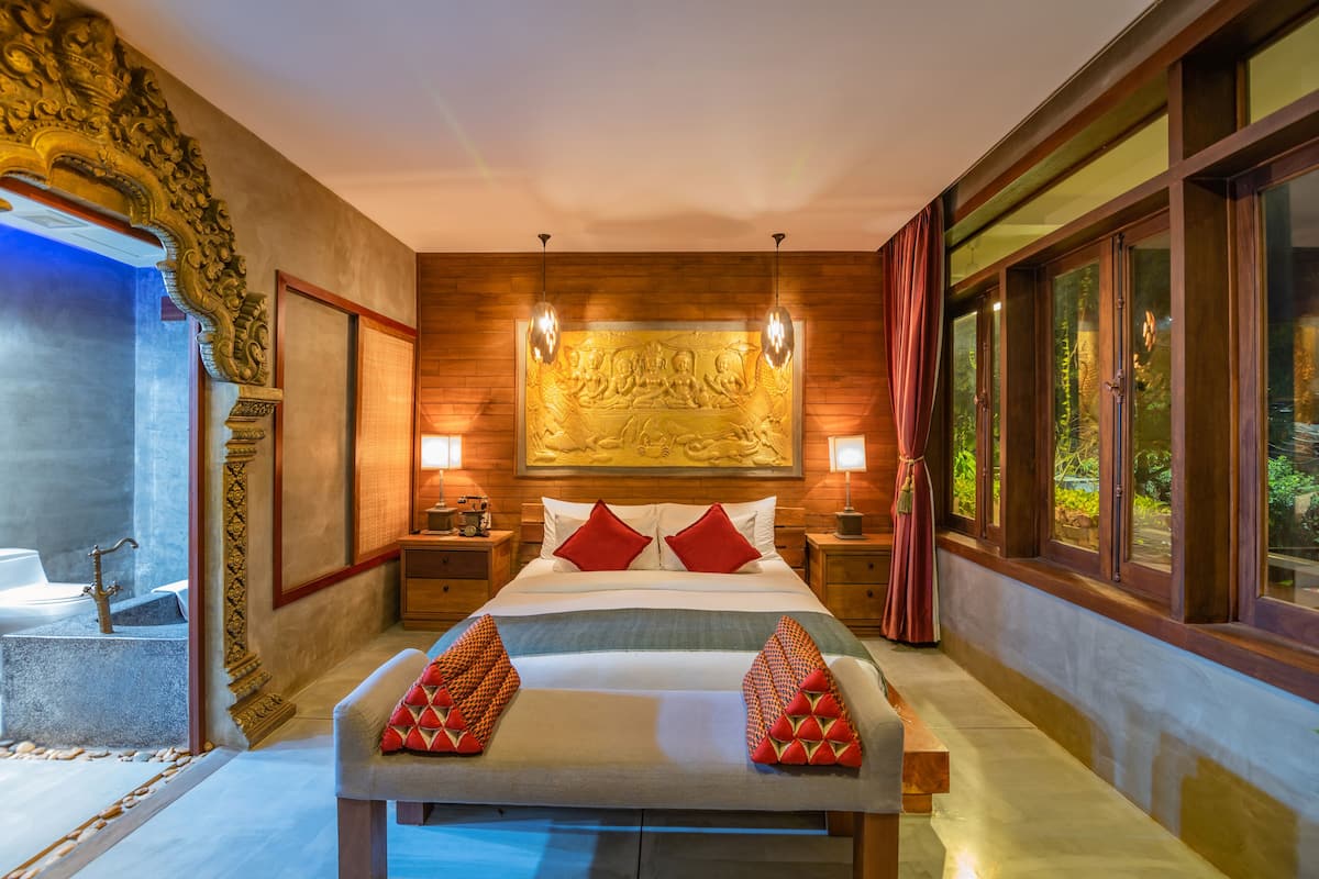 A spacious bedroom with a large bed, two bedside tables, a wall-mounted artwork, and large windows.