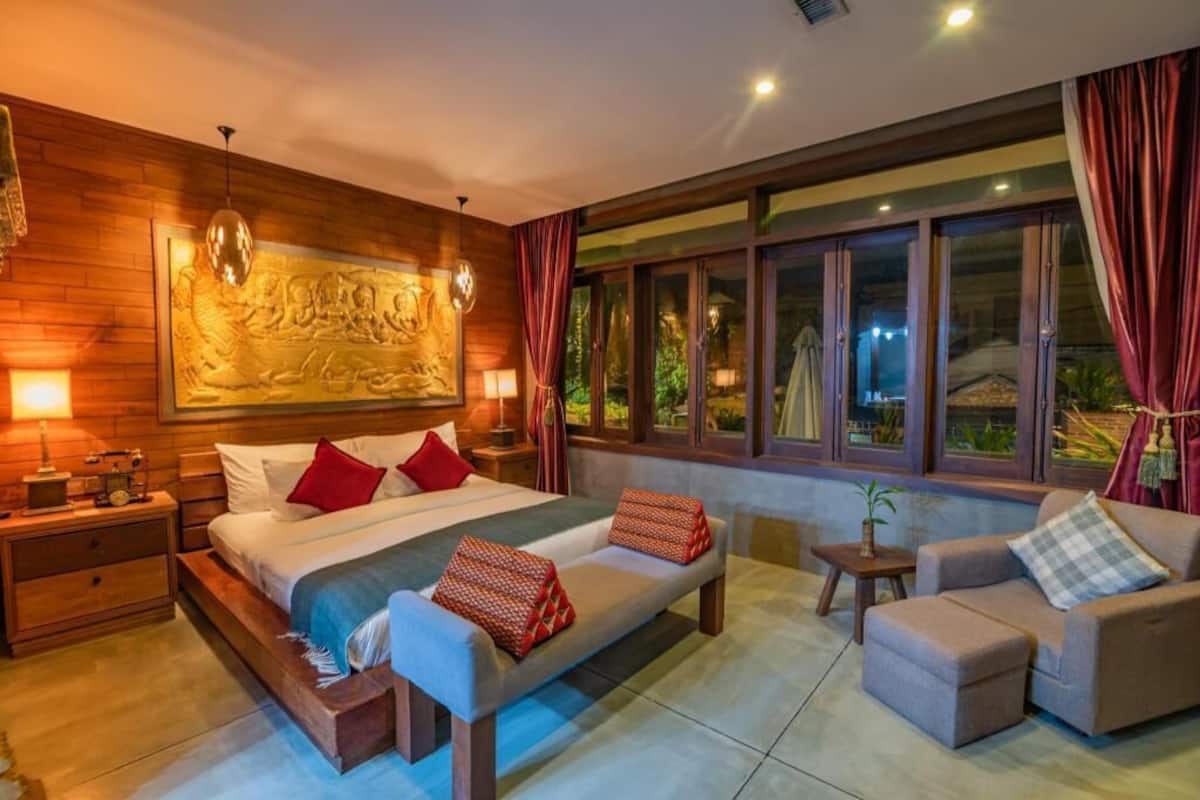 A bedroom with a bed, bedside tables, a sofa, and a window with curtains.