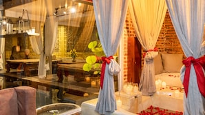 A cozy room with a bed, a window with curtains, and a small table with candles. - Cambana d'Angkor Suites (Siem Reap)