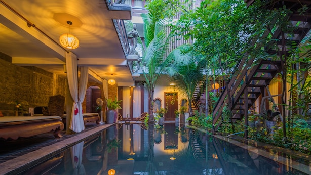 A luxurious indoor pool area with a glass floor, surrounded by lush greenery and a staircase leading to upper levels. - Cambana d'Angkor Suites (Siem Reap)