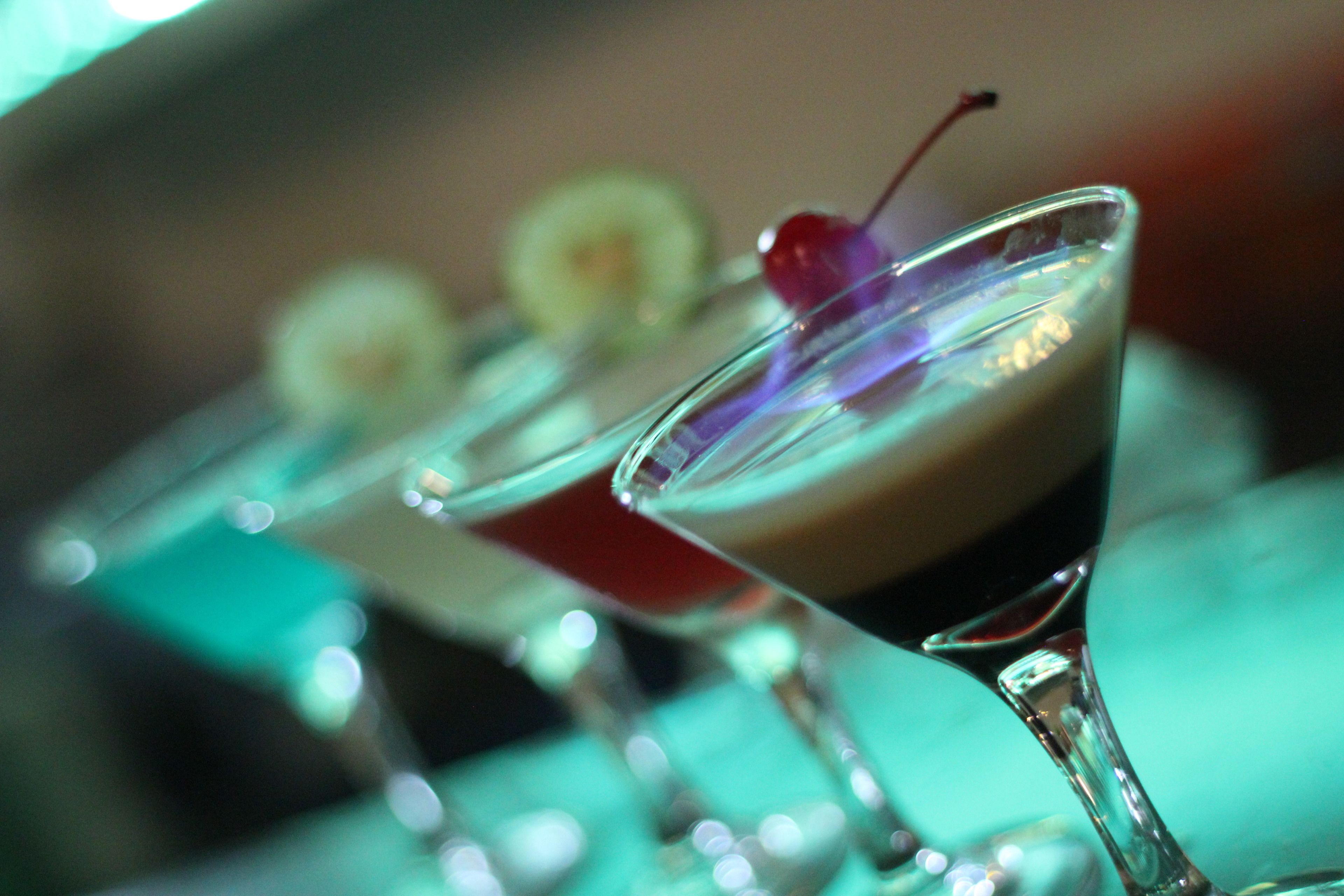 Primer plano de una barra con diversas bebidas en copas de martini.