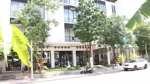 A modern building with a covered entrance, outdoor seating, and a parked car. - Landing Gold By Amatak (Siem Reap)