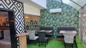 Un restaurante con una decoración moderna, que presenta un suelo de césped artificial verde, paredes con un diseño blanco y negro y un atril de madera.