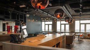 Un espacio de oficina moderno con mostrador de recepción, ventanas amplias e iluminación de estilo industrial.